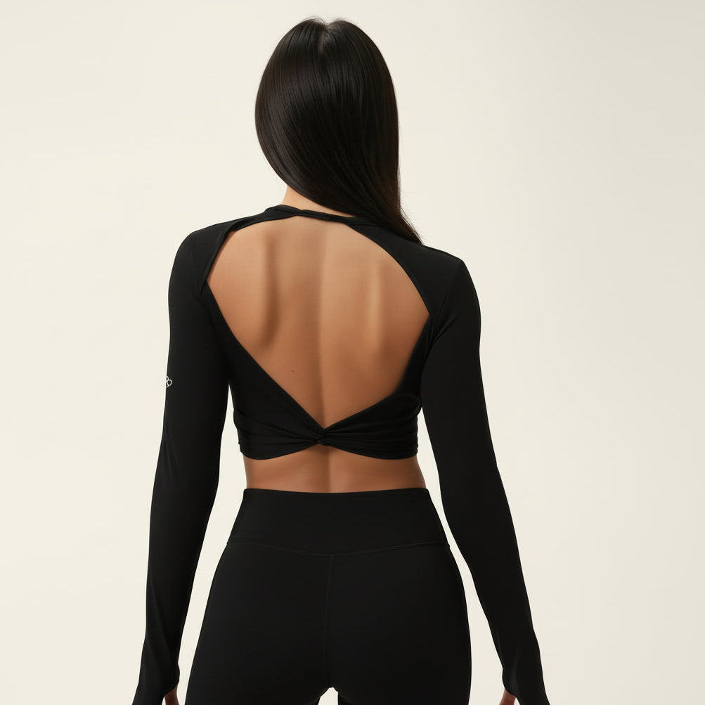 Black long-sleeve crop top with open back worn by a woman on a beige background