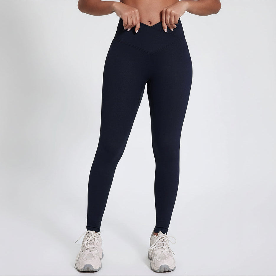 Model wearing black v-waist leggings and white sneakers on a light gray background