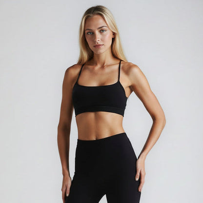 Woman wearing a black sports bra and leggings on a plain background