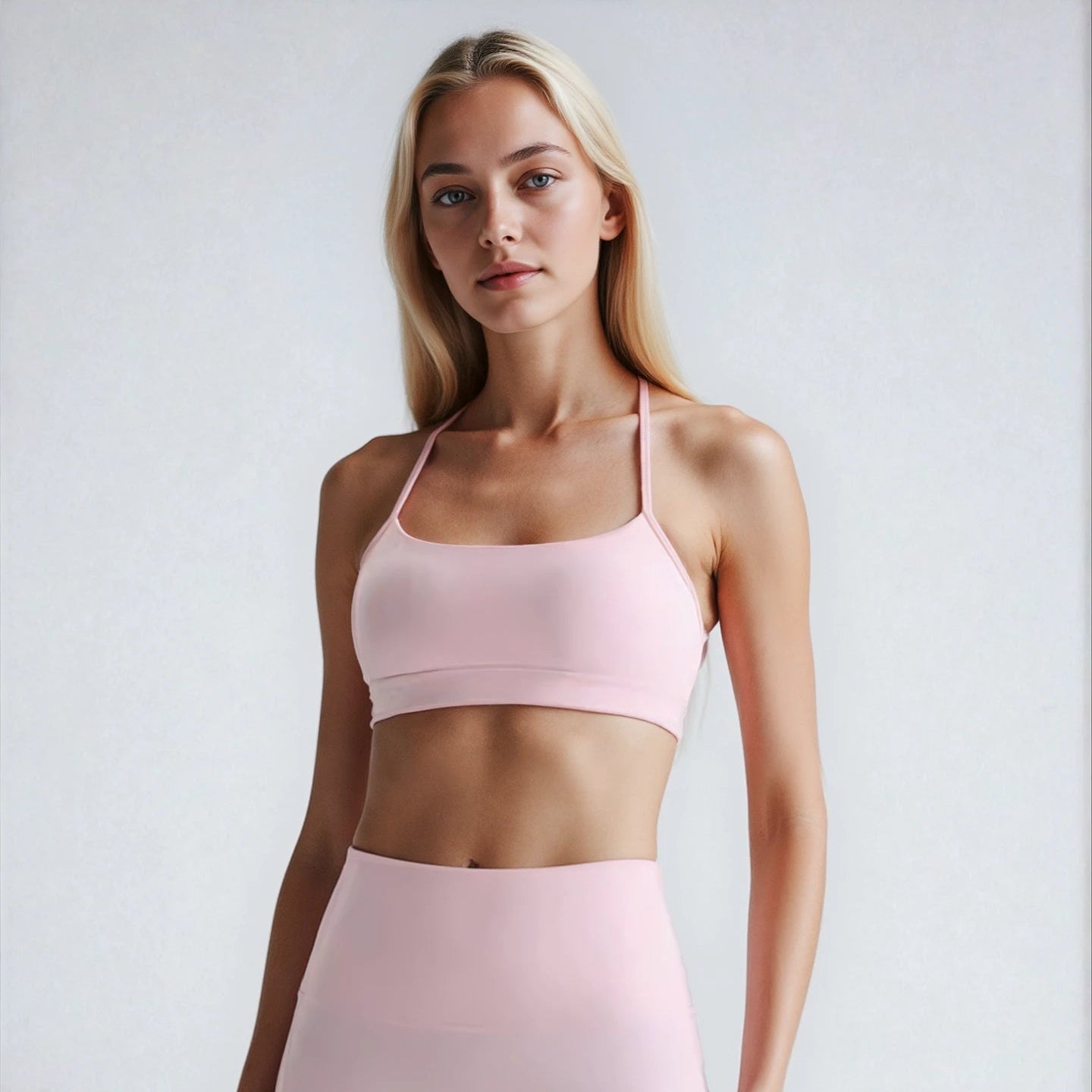 Woman wearing a soft pink sports bra and high-waisted shorts on a white background