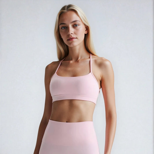 Woman wearing a soft pink sports bra and high-waisted shorts on a white background