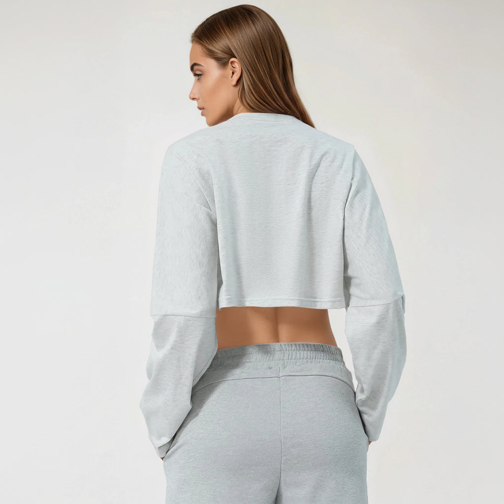 Woman wearing a light gray cropped tshirt and pants on a white background