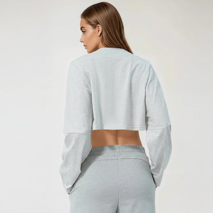 Woman wearing a light gray cropped tshirt and pants on a white background