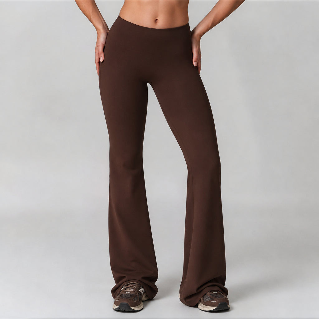 A model modeling a pair of dark brown high-waisted flared leggings, shown from the waist down against a light gray studio background.