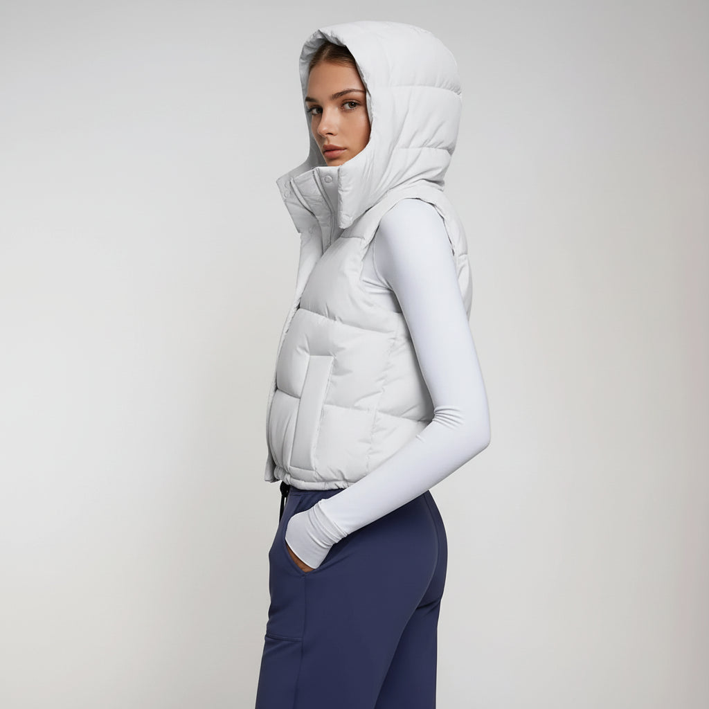 Woman wearing a white puffer vest with a hood against a gray background